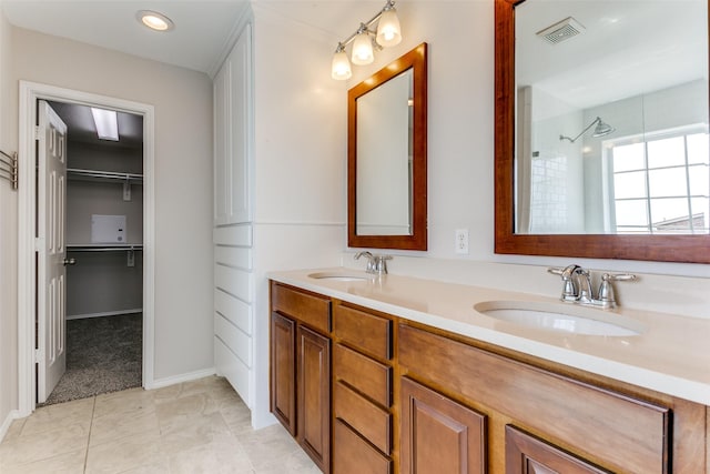 full bathroom featuring double vanity, visible vents, a tile shower, and a sink