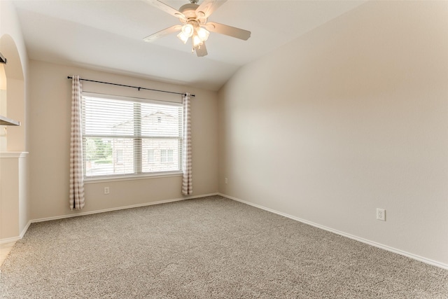 empty room featuring lofted ceiling, ceiling fan, carpet floors, and baseboards