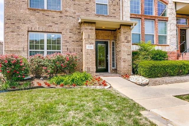 doorway to property with a yard and brick siding