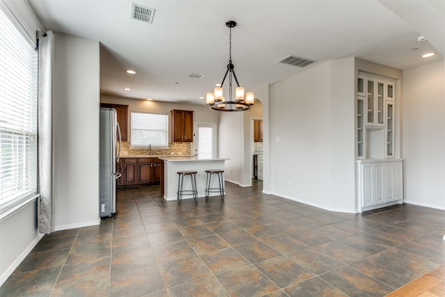 kitchen with visible vents, a kitchen island, freestanding refrigerator, and light countertops
