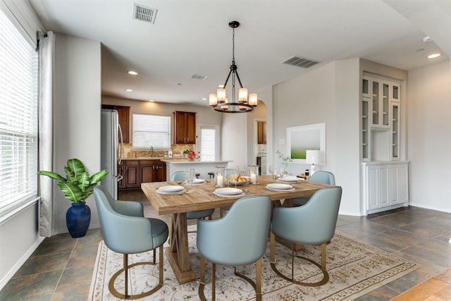 dining room featuring baseboards, visible vents, and an inviting chandelier