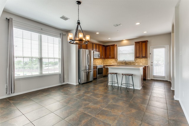 kitchen with appliances with stainless steel finishes, a chandelier, light countertops, and visible vents