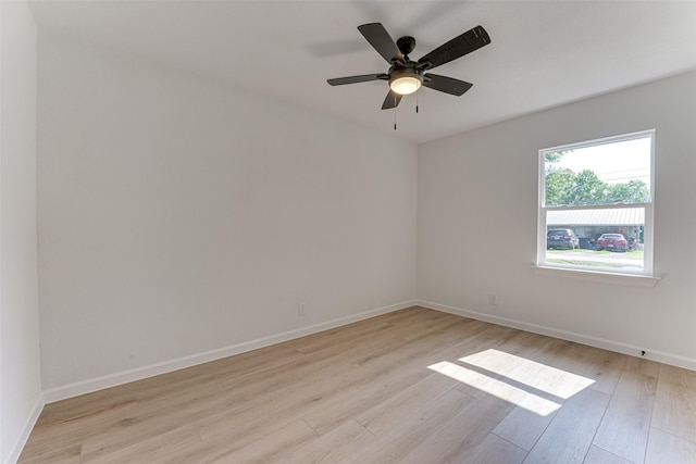 empty room featuring light wood finished floors, a ceiling fan, and baseboards