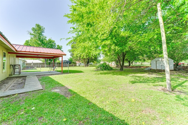 view of yard featuring a patio, a storage unit, a fenced backyard, and an outbuilding