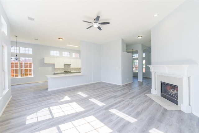7404 Maybrook Ct, Plano, TX 75024 - unfurnished living room featuring light wood finished floors, ceiling fan, baseboards, a chandelier, and healthy amount of natural light