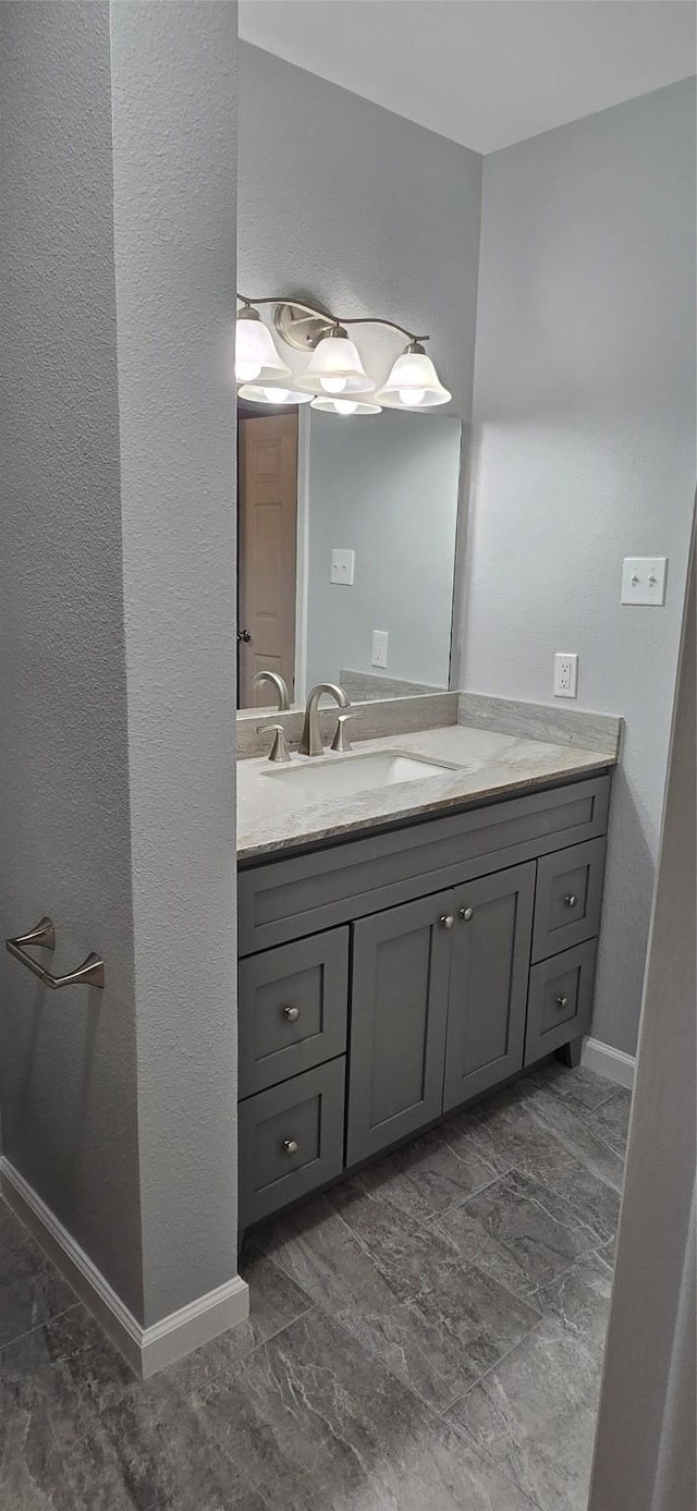 bathroom with a textured wall, vanity, and baseboards