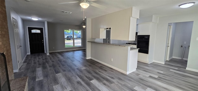 kitchen with white cabinets, ceiling fan, stone countertops, oven, and wood finished floors