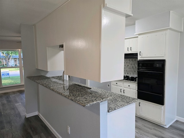 kitchen featuring black appliances, wood finished floors, a warming drawer, and white cabinets
