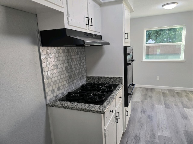 kitchen with white cabinetry, light wood-style floors, black appliances, a warming drawer, and backsplash