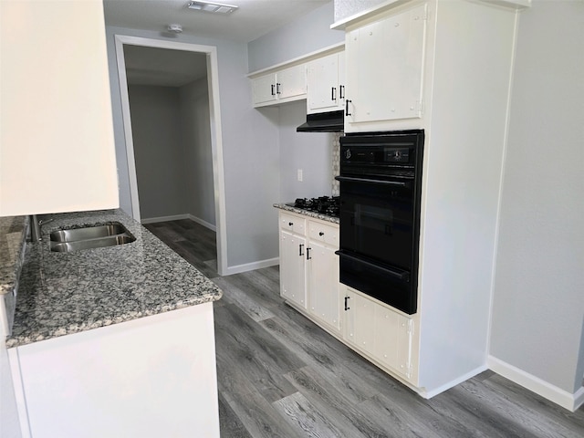 kitchen with a warming drawer, black appliances, a sink, and stone countertops