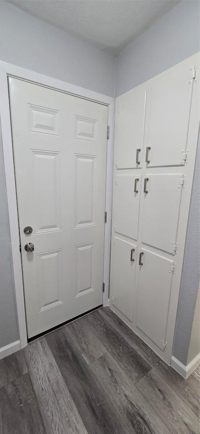 doorway to outside with dark wood-style floors and baseboards