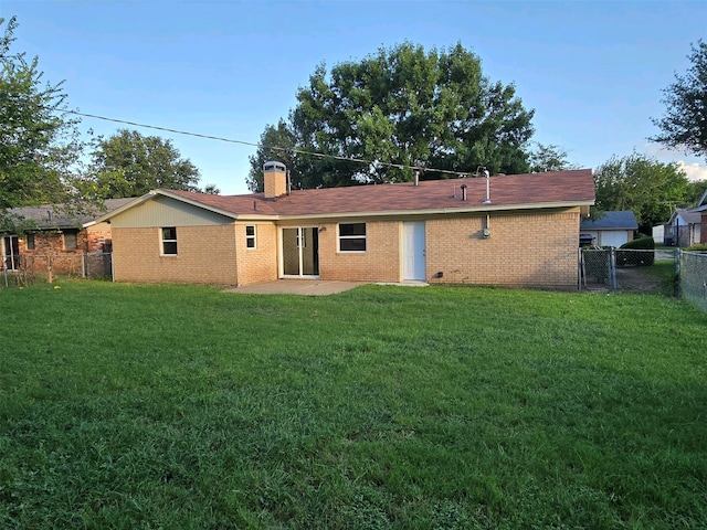 back of property featuring a chimney, a yard, brick siding, fence, and a patio