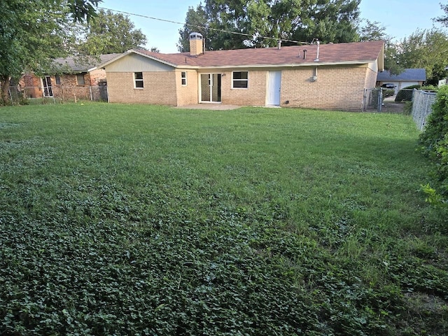 rear view of house with fence, a lawn, and brick siding