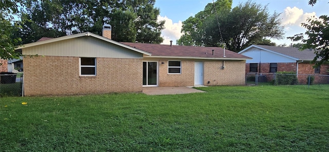 back of property with fence, a lawn, and brick siding