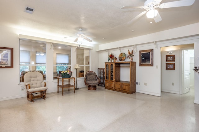 living area with baseboards, visible vents, and ceiling fan