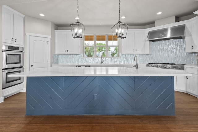 727 S Sugartree Dr, Lipan, TX 76462 - kitchen with wall chimney range hood, white cabinets, stainless steel appliances, an inviting chandelier, and a kitchen island with sink
