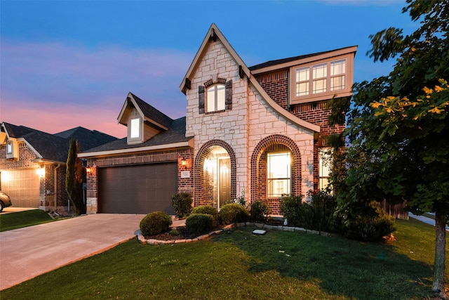 view of front of house with a lawn, a garage, brick siding, and stone siding