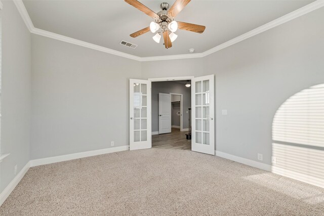 carpeted empty room featuring ornamental molding, ceiling fan, baseboards, visible vents, and french doors