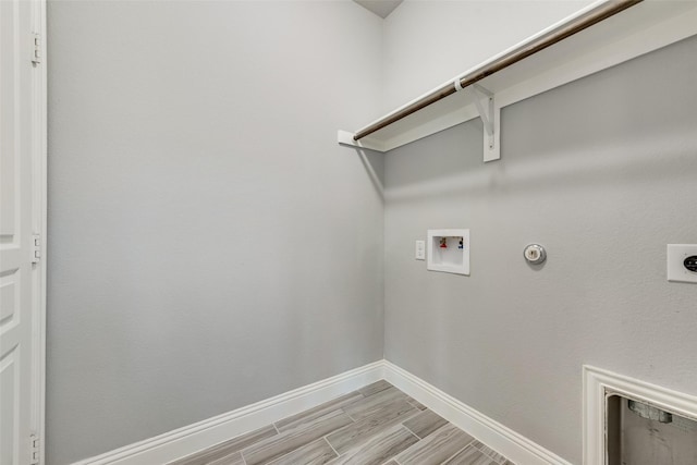 clothes washing area with laundry area, hookup for an electric dryer, washer hookup, light wood finished floors, and baseboards