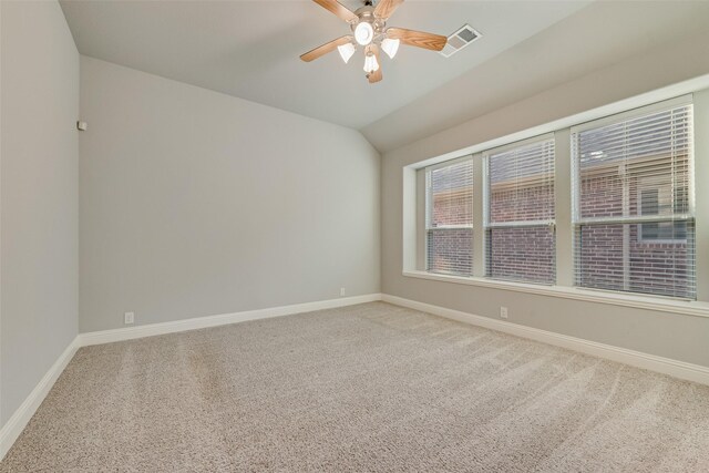 carpeted spare room with lofted ceiling, visible vents, ceiling fan, and baseboards