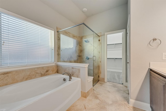 bathroom featuring a shower stall, vanity, a bath, baseboards, and a spacious closet