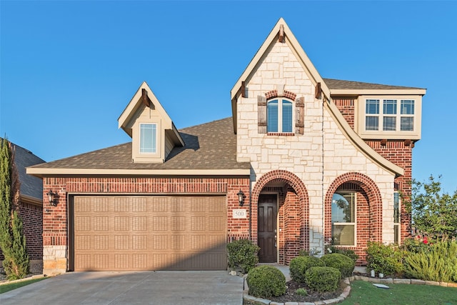 view of front of house with a garage, concrete driveway, brick siding, and stone siding