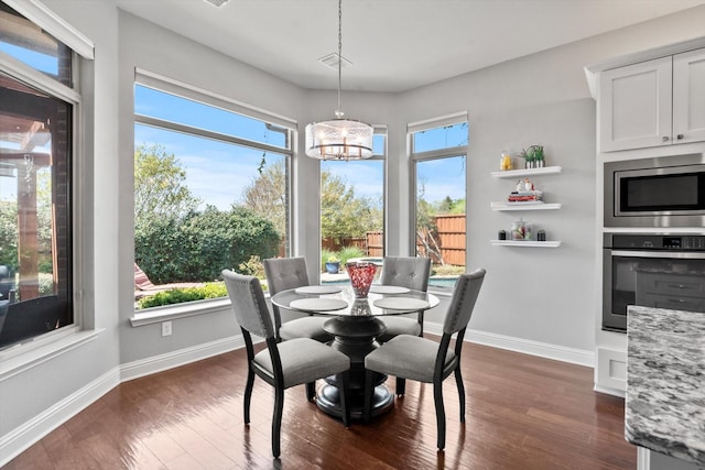 dining room with dark wood finished floors, baseboards, and a notable chandelier