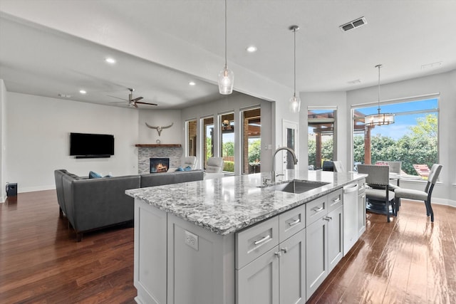 kitchen featuring dark wood finished floors, recessed lighting, a stone fireplace, and a sink