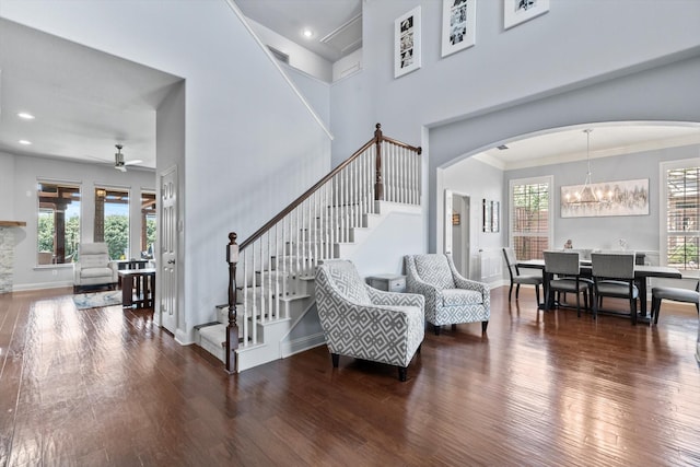 entryway with stairway, arched walkways, ceiling fan with notable chandelier, and wood finished floors