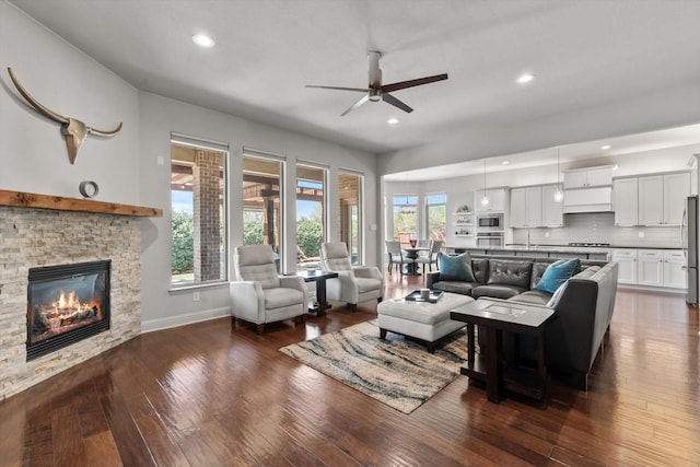 living area featuring recessed lighting, ceiling fan, dark wood-style flooring, a fireplace, and baseboards