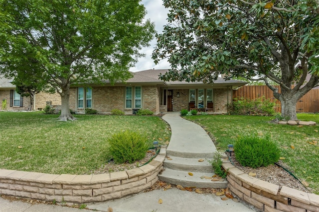 single story home featuring brick siding, fence, and a front yard