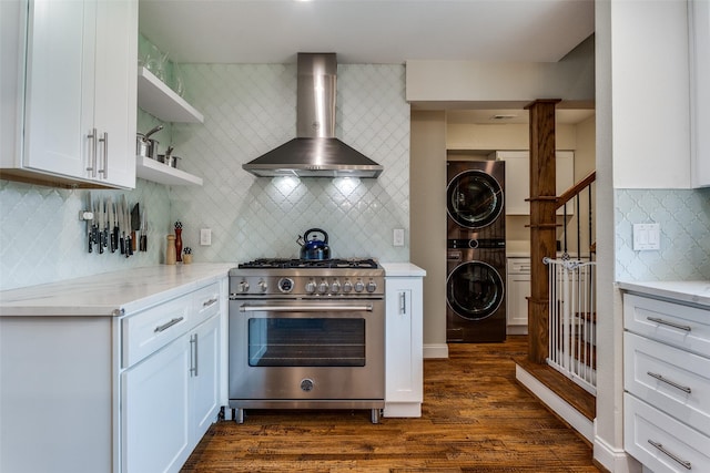 kitchen with dark wood-style floors, high end range, tasteful backsplash, wall chimney range hood, and stacked washer / dryer
