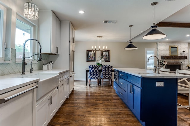 kitchen with a sink, a notable chandelier, blue cabinets, and dark wood-type flooring