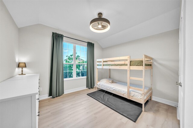 bedroom with baseboards, light wood finished floors, and lofted ceiling