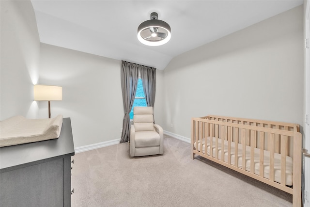 bedroom featuring a crib, carpet flooring, vaulted ceiling, and baseboards