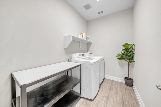 laundry area with light wood-style floors, visible vents, washing machine and clothes dryer, and laundry area