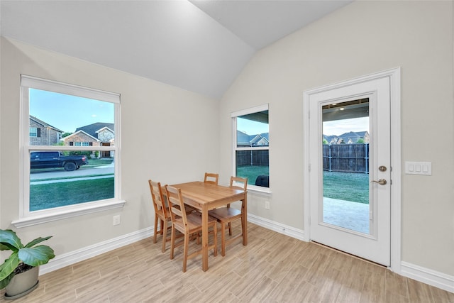 dining space with lofted ceiling, light wood-style floors, and baseboards