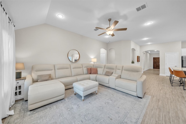 living area featuring arched walkways, light wood-style floors, ceiling fan, baseboards, and visible vents