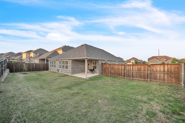 back of property featuring a patio area, a shingled roof, a yard, brick siding, and a fenced backyard