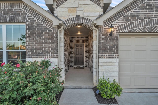doorway to property with stone siding, brick siding, and a garage