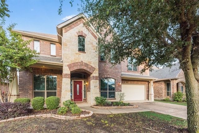 view of front of home with a garage, brick siding, concrete driveway, and stone siding