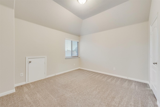 spare room with vaulted ceiling, carpet, and baseboards