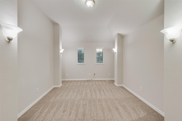 interior space with light colored carpet, vaulted ceiling, and baseboards