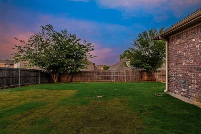 yard at dusk featuring a fenced backyard