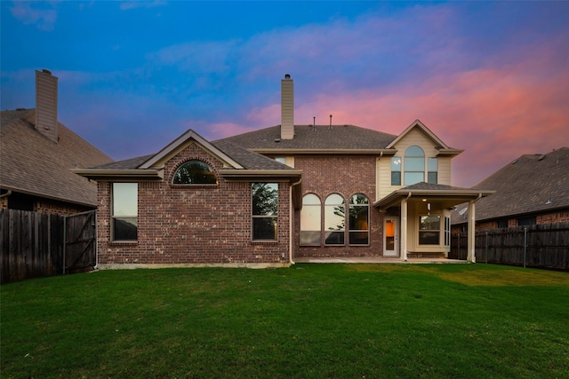 back of property with a patio, a yard, a fenced backyard, and brick siding