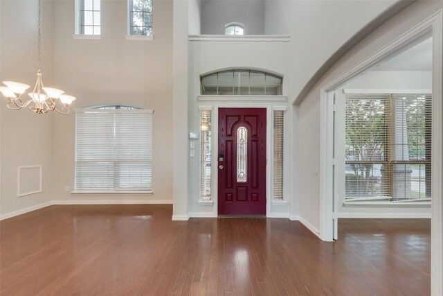 entrance foyer with baseboards, wood finished floors, a notable chandelier, and a high ceiling