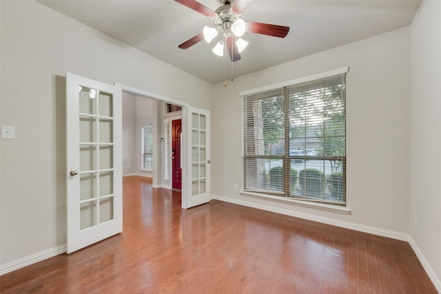 empty room with ceiling fan, wood finished floors, french doors, and baseboards
