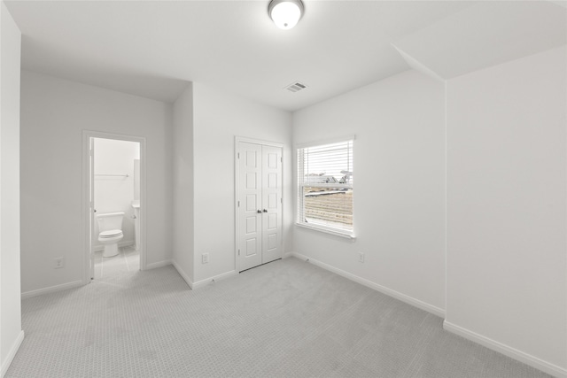 unfurnished bedroom with connected bathroom, a closet, visible vents, light carpet, and baseboards