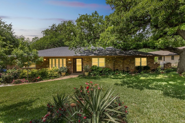 ranch-style house with a lawn and brick siding