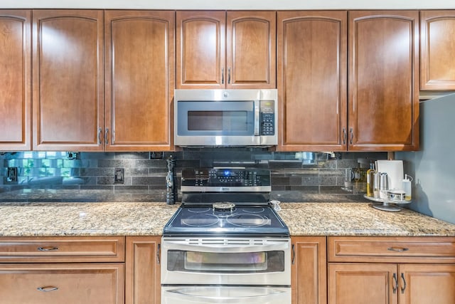 kitchen featuring backsplash, light stone countertops, and appliances with stainless steel finishes